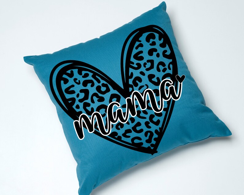May include: A teal blue cushion with a black heart-shaped design featuring a leopard print pattern. The word "mama" is written in a black cursive font inside the heart.