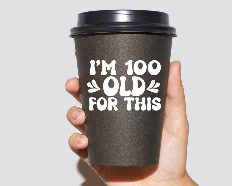 May include: A black to-go coffee cup with a white graphic that reads "I'm 100 Old For This".