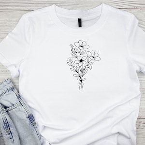 May include: A white t-shirt with a black line drawing of a bouquet of flowers.