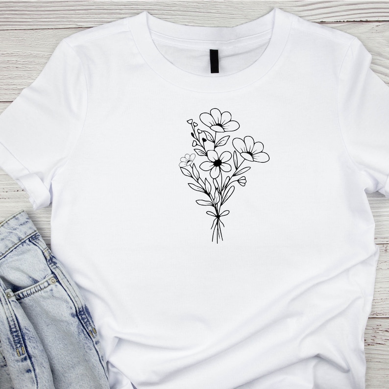 May include: A white t-shirt with a black line drawing of a bouquet of flowers.