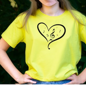 May include: A yellow t-shirt with a black heart design featuring a treble clef and musical notes.