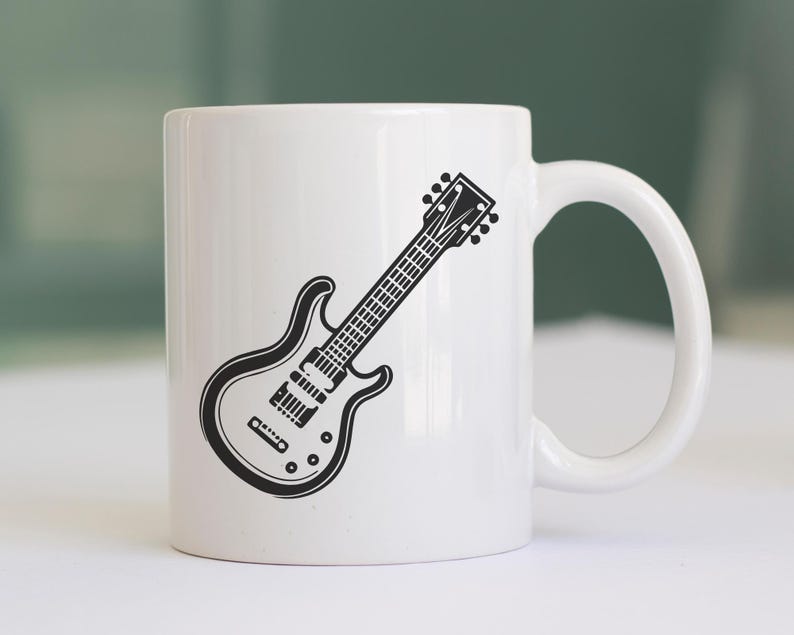 May include: White ceramic mug featuring a black and white illustration of an electric guitar. The guitar design is detailed, showing the strings, pickups, and tuning pegs. The mug has a curved handle and a smooth, glossy finish.