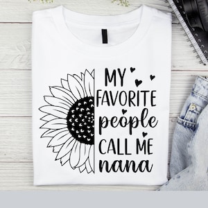 May include: White t-shirt with a black sunflower graphic and the text "My favorite people call me nana" with small hearts.