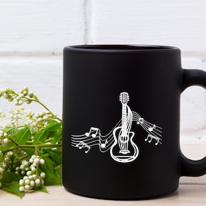May include: Black coffee mug with a white outline of a guitar and musical notes. The mug is on a white brick background.