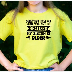 May include: Yellow t-shirt with black text that reads "Sometimes I feel old *but then I* realized my sister is older".