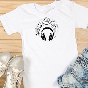 May include: White t-shirt with a black graphic of headphones and musical notes.