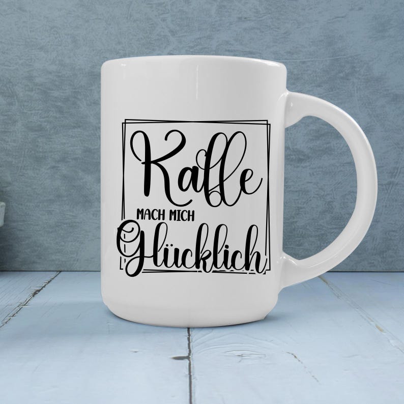May include: White ceramic coffee mug with a black script design that reads "Kaffe MACH MICH Gl&uuml;cklich!" The mug has a large handle and is set against a light blue background. A perfect gift for coffee lovers.