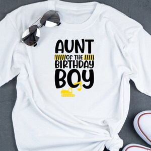 May include: White t-shirt with black text that reads "Aunt of the Birthday Boy" with yellow and black stripes and a small yellow construction vehicle graphic.