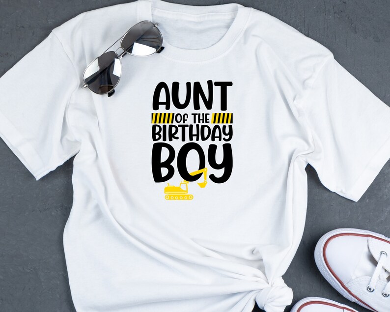 May include: White t-shirt with black text that reads "Aunt of the Birthday Boy" with yellow and black stripes and a small yellow construction vehicle graphic.