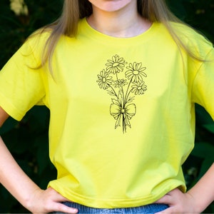 May include: A yellow t-shirt with a black line drawing of a bouquet of daisies tied with a bow.