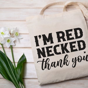 以下が含まれることがあります： 黒い文字で「I'm Red Necked, thank you」と書かれた白いキャンバス地のトートバッグです。