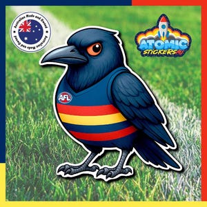 May include: A sticker of a cartoon crow wearing a blue, yellow, and red jersey with the AFL logo. The crow has orange eyes and is set against a green and white background. The sticker has a white border and the text "Atomic Stickers AU".