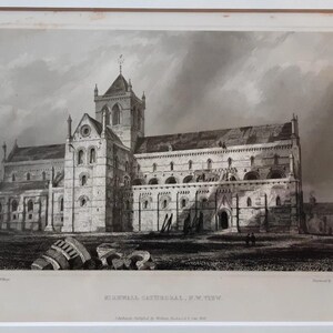 May include: Black and white print of a cathedral, framed in white. The artwork depicts a detailed architectural rendering of the building, with a prominent tower and arched windows. The print is mounted on a white mat, and the title "Rievaulx Abbey, N.W. View" is visible.