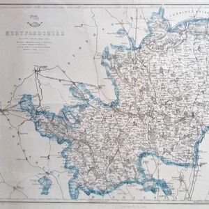 May include: Antique map of Hertfordshire, England, with detailed cartography. The map features a blue border and text, including the county name. The paper has a vintage appearance, with visible creases and age spots.