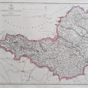 May include: An antique map of Somerset, England, showing detailed geographical features. The map has a pink border and text including "Bristol Channel." Printed on aged paper, it is a historical document.