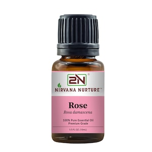 Könnte beinhalten: Kleine bernsteinfarbene Glasflasche mit ätherischem Rosenöl von Nirvana Nurture. Das Etikett ist weiß und rosa mit dem Text "Rose Rosa damascena" und "100% Pure Essential Oil". Die Flasche hat einen schwarzen Deckel und enthält 10 ml Öl.
