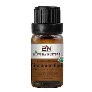 May include: A small amber glass bottle of Nirvana Nurture Cinnamon Bark essential oil. The bottle has a black cap and a label with the brand name, product name, and USDA Organic certification. The bottle contains 1/3 fl oz (10ml) of oil.