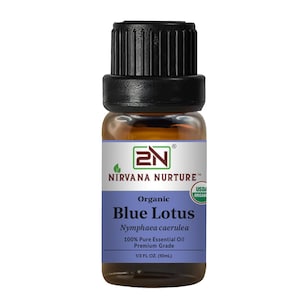 Könnte beinhalten: Kleine Glasflasche mit ätherischem Öl von Nirvana Nurture Organic Blue Lotus. Das Etikett zeigt "Blue Lotus" und "100% reines ätherisches Öl". Die Flasche enthält 10 ml. Die Flasche hat einen schwarzen Deckel und ein blau-weißes Etikett.