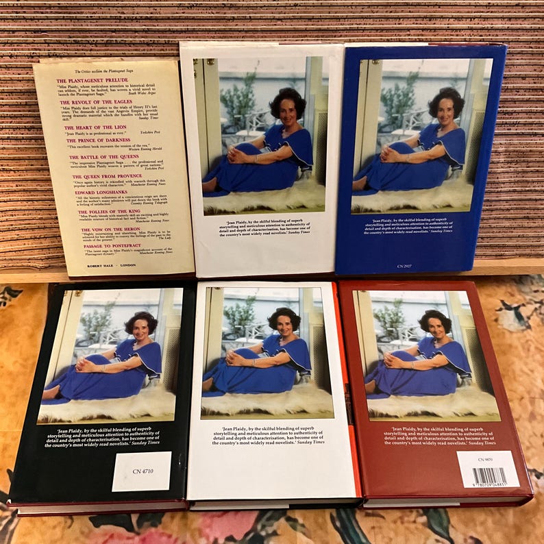 Puede incluir: Una colecci&oacute;n de libros antiguos con cubiertas de varios colores. Los libros presentan un retrato de una mujer con un vestido azul. Las lomos muestran t&iacute;tulos como "The Plantagenet Prelude" y "The Heart of the Lion."