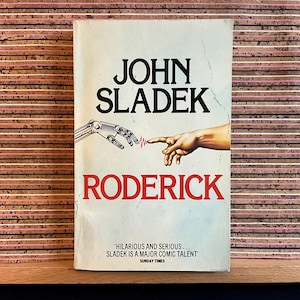 May include: A book cover with a white background and a red title, "RODERICK." The author's name, "JOHN SLADEK," is in black text above the title. The cover features a robotic hand reaching out to touch a human hand. The text "'HILARIOUS AND SERIOUS... SLADEK IS A MAJOR COMIC TALENT' SUNDAY TIMES" is at the bottom of the cover.