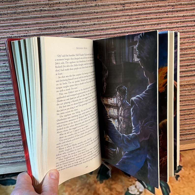 May include: An open book with red edges, featuring text and illustrations. The pages display printed text and a full-page illustration of a man in a suit. The book is likely a novel or a collection of stories.