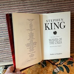 May include: An open book by Stephen King, titled "Wolves of the Calla," from The Dark Tower series. The cover features the author's name and title in bold black font. The book is published by Hodder & Stoughton.