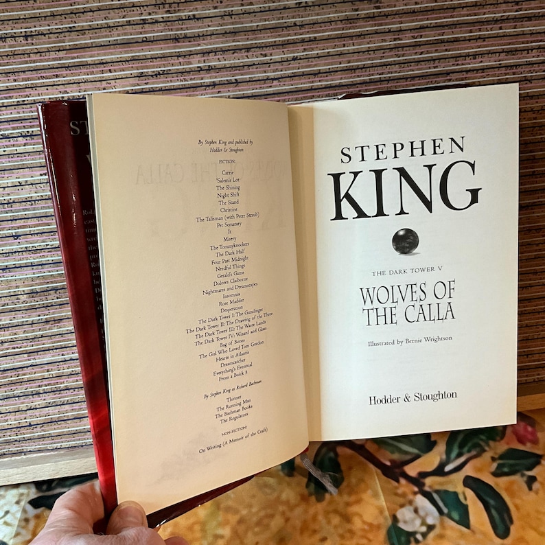 May include: An open book by Stephen King, titled "Wolves of the Calla," from The Dark Tower series. The cover features the author's name and title in bold black font. The book is published by Hodder & Stoughton.