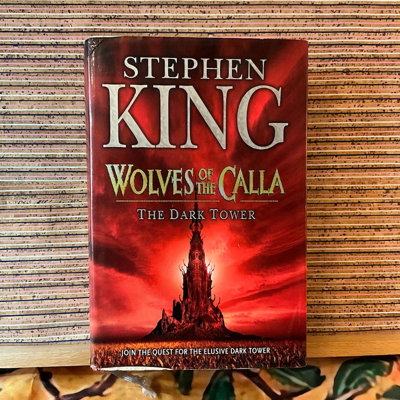 May include: A hardcover book titled "Wolves of the Calla" by Stephen King. The cover features a dark red background with a silhouetted tower and the text "The Dark Tower." The book's title and author's name are prominently displayed.