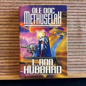 May include: A hardcover book titled "Ole Doc Methuselah" by L. Ron Hubbard. The cover art features a science fiction scene with a figure in a blue cape, a futuristic vehicle, and the text "The Intergalactic Adventures of the Soldier of Light."