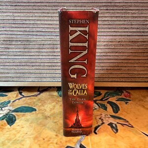 May include: A book spine with the title "Wolves of the Calla" by Stephen King. The spine is predominantly red with white lettering. A dark illustration of a castle is at the bottom. The book is part of "The Dark Tower" series.