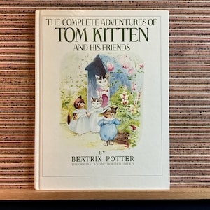 May include: A hardback book titled "THE COMPLETE ADVENTURES OF TOM KITTEN AND HIS FRIENDS" by Beatrix Potter. The cover shows an illustration of kittens in clothes, near a blue structure with flowers. It is the original and authorised edition.