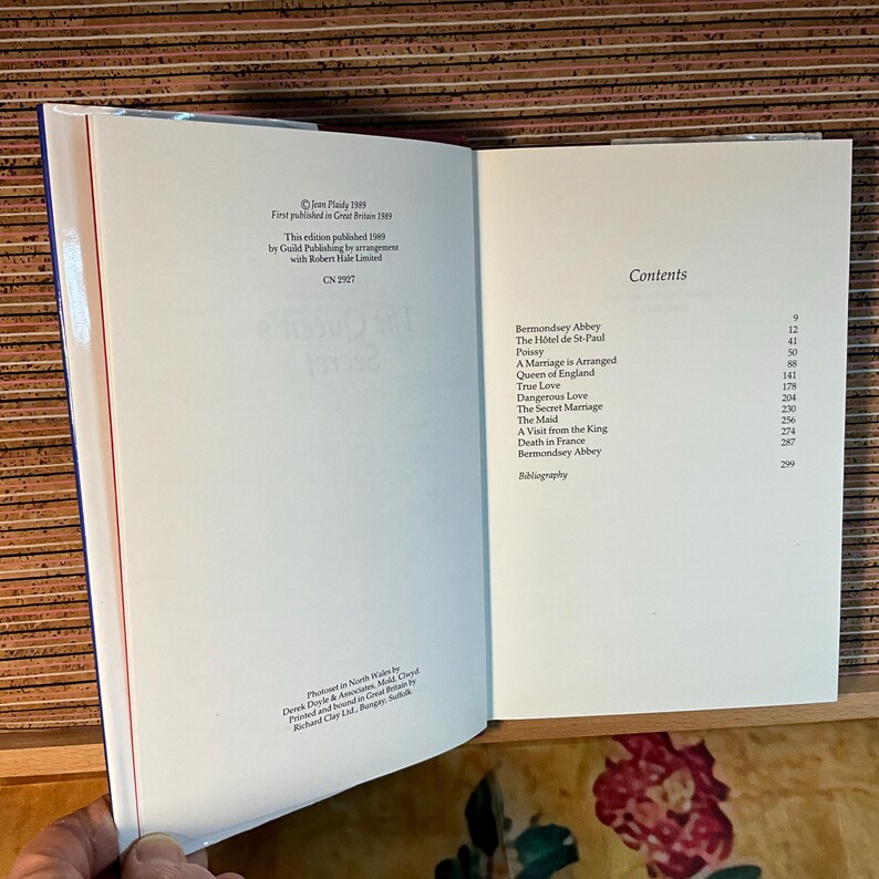 Puede incluir: Libro abierto con p&aacute;ginas blancas, que muestra texto y una tabla de contenidos. La p&aacute;gina izquierda tiene detalles de publicaci&oacute;n. La p&aacute;gina derecha enumera los t&iacute;tulos de los cap&iacute;tulos y los n&uacute;meros de p&aacute;gina. El libro est&aacute; abierto sobre una superficie de madera.
