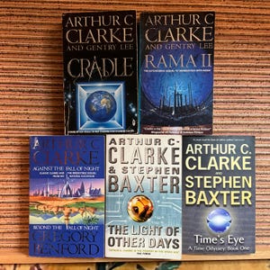 Könnte beinhalten: Eine Sammlung von Science-Fiction-Büchern von Arthur C. Clarke und anderen Autoren. Zu den Titeln gehören "Cradle", "Rama II", "Against the Fall of Night", "The Light of Other Days" und "Time's Eye". Die Bücher haben farbenfrohe Umschläge mit verschiedenen Illustrationen.