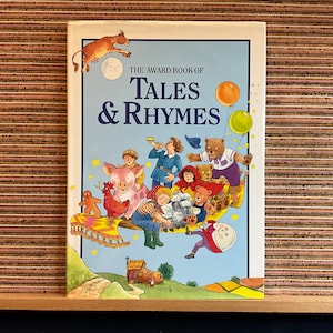 May include: A colorful book cover with the title "The Award Book of Tales & Rhymes". The cover features illustrations of animals, children, and a flying carpet.