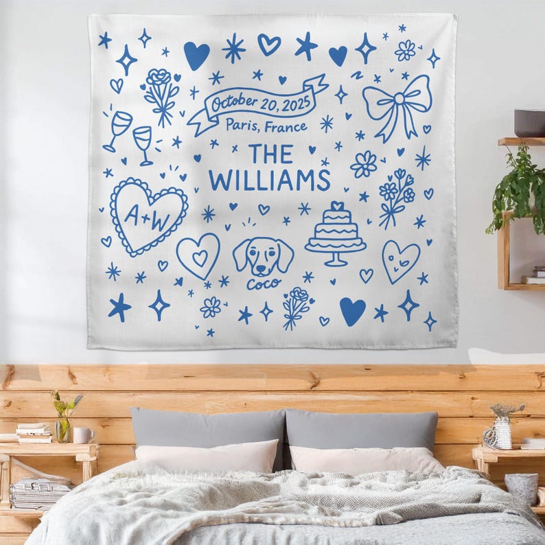 May include: White wall tapestry with blue doodle-style illustrations of hearts, flowers, stars, and a bow. Text includes "October 20, 2025, Paris, France" and "THE WILLIAMS". Features a heart with "A+W" and a dog named "Coco".