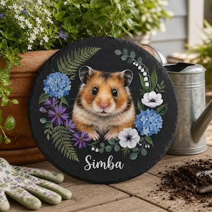 Könnte beinhalten: Eine runde schwarze Schieferplatte mit einer zentralen Illustration eines braun-weißen Hamsters, umgeben von einem Kranz aus blauen Hortensien, violetten Blumen, weißen Anemonen und grünen Farnen, mit dem Namen Simba in weißer Schrift.