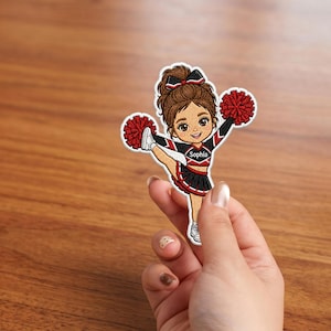 Puede incluir: Un parche bordado que muestra a una animadora de dibujos animados con cabello castaño en una coleta alta, vistiendo un uniforme negro y rojo con el nombre Sophia impreso en el pecho, sosteniendo dos pompones rojos en una pose de patada alta.