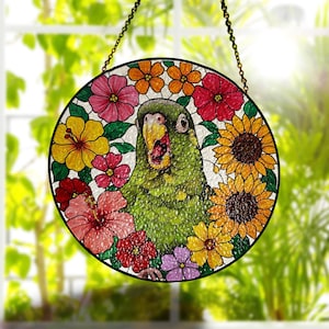 May include: A stained glass window hanging features a green parrot with a yellow beak surrounded by colorful flowers and sunflowers.