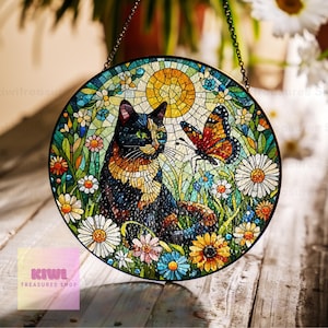 Pode incluir: Um apanhador de sol redondo de vidro colorido com um gato preto, laranja e branco sentado em um campo de flores coloridas com uma borboleta voando acima. O apanhador de sol é feito de peças de vidro em mosaico e tem uma corrente para pendurar.