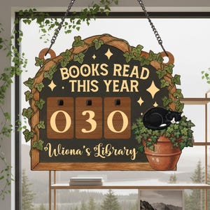 May include: Wooden sign with the text "BOOKS READ THIS YEAR" and the number "030". The sign is decorated with ivy and a sleeping black and white cat in a pot. The sign also says "Uliona's Library".