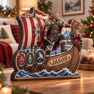 May include: A wooden decorative cutout featuring a Viking warrior standing on a longship with a red and white striped sail marked with a black symbol. The ship displays three circular shields, a dragon figurehead, and the name JASON engraved.