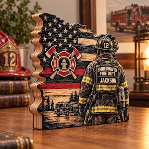 May include: A layered wooden sign shaped like the state of Oregon, featuring a distressed American flag with a thin red line, a firefighter emblem, a fire truck, and a firefighter wearing gear labeled Emberhaven Fire Dept Jackson.