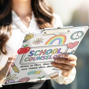 May include: A clear clipboard with colorful illustrations and the words "SCHOOL COUNSELOR" in rainbow colors. The clipboard features a rainbow, apple, clock, and other doodles. Text at the bottom reads "Listen to them, Love them and Watch Them Grow."
