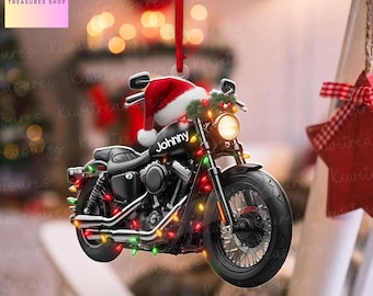 Puede incluir: Adorno navideño de motocicleta negra con gorro de Papá Noel y luces de cadena. La palabra "Johnny" está en el lateral de la motocicleta. El adorno cuelga de una cinta roja.