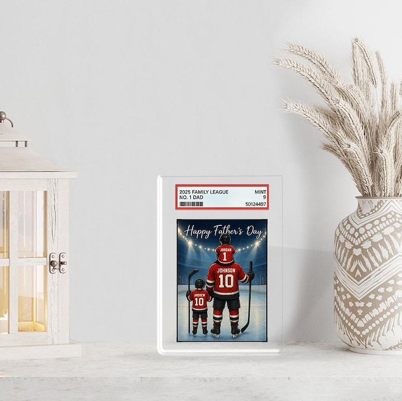 May include: A framed print featuring a father and child in hockey uniforms, with the text "Happy Father's Day." The father's jersey reads "Jordan 10," and the child's reads "Andrew 10." The print is encased in a clear protective holder.