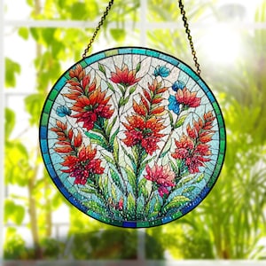May include: A round stained glass window hanging from a chain. The window features a colourful floral design with red, orange, yellow, blue, and green flowers. The flowers are surrounded by a green leafy design.