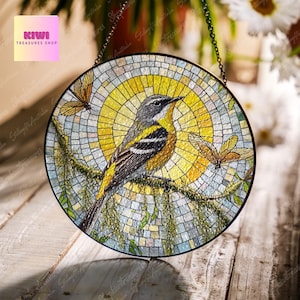 May include: A round stained glass suncatcher with a mosaic design featuring a yellow bird perched on a branch with green leaves. The suncatcher also features a butterfly with orange wings. The suncatcher is hanging from a chain.
