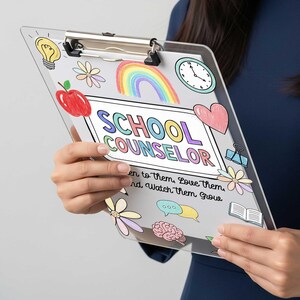 May include: Clear clipboard with a metal clip, featuring colorful illustrations of a rainbow, apple, flowers, and a clock. The text "SCHOOL COUNSELOR" is prominently displayed, along with the phrase "Listen to them, Love them, and Watch them Grow."