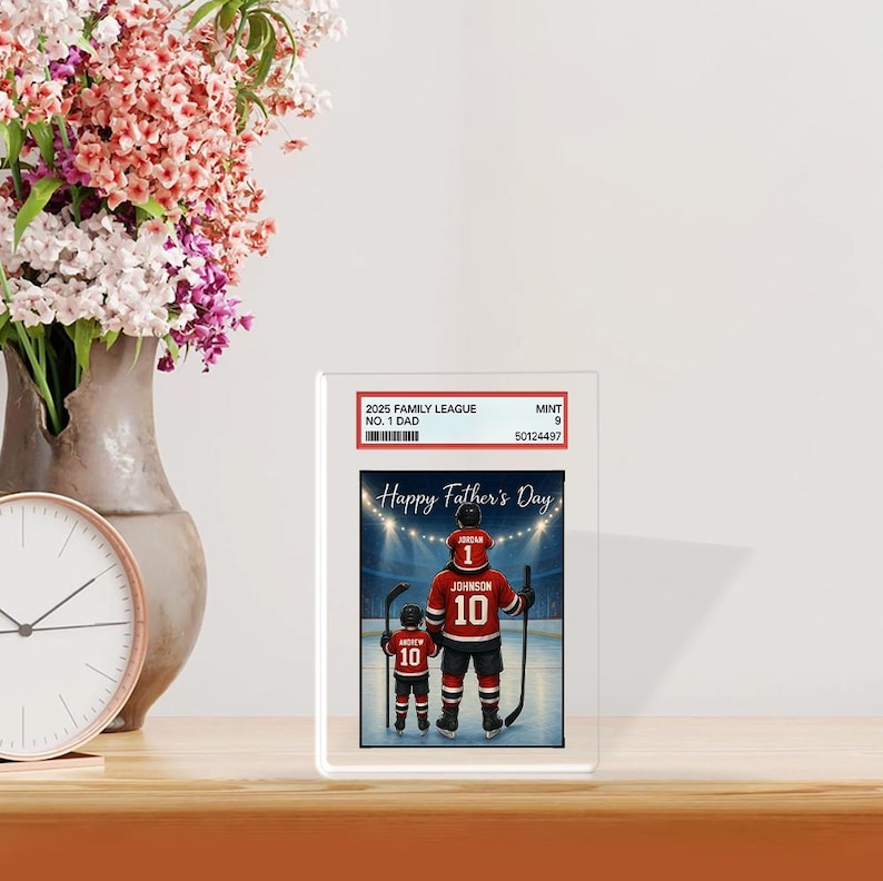 May include: A framed print featuring a hockey-themed illustration for Father's Day. The image shows a father and child in hockey jerseys with the text "Happy Father's Day". The jerseys have the number 10 and the name "Johnson".