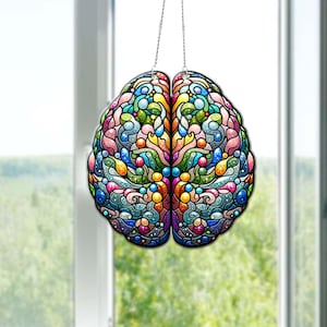 Könnte beinhalten: Ein farbenfroher Gehirnschmuck im Stil von Buntglas, der an einer silbernen Kette hängt. Das Gehirn besteht aus Wirbeln und Punkten in Blautönen, Grün, Gelb, Rosa und Lila.
